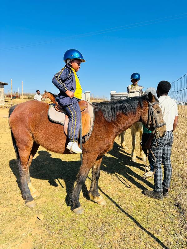 A pupil in a riding helmet on horseback