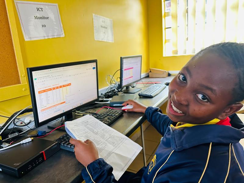 A pupil at a desktop computer turning to smile at the camera