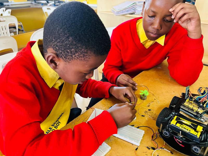 Two pupils assembling a robotics kit at a workbench